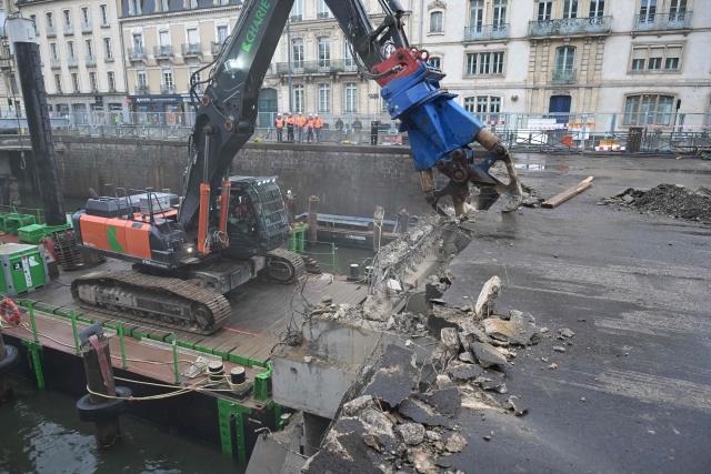 Workers use an excavator, mounted on a barge, to chip away the slab of a car park and uncover the Vilaine river, in the city centre of Rennes, western France on December 16, 2025. (Photo by Damien MEYER / AFP)
