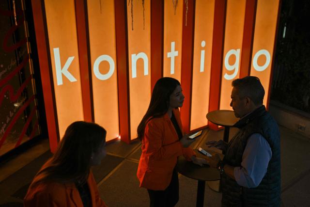 People attend an event to launch the “Kontigo” cryptocurrency app in Caracas on December 15, 2025. (Photo by Federico PARRA / AFP)
