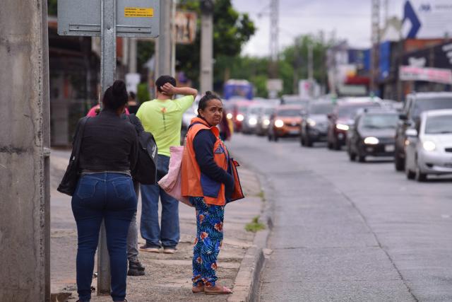 People wait at a bus stop during a two-day strike of drivers in Asuncion, on December 16, 2025. Drivers are protesting against a transport reform law and the measure affects 80% of the service of the Paraguayan capital and surroundings. (Photo by DANIEL DUARTE / AFP)