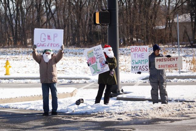 Anti-Trump demonstrators hold signs before the Vice Presidential motorcade outside Uline Inc. in Allentown, Pennsylvania on December 16, 2025. (Photo by Tom BRENNER / POOL / AFP)