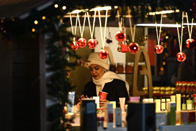 An Iraqi woman visits a Christmas market at an amusement park in Basra on December 16, 2025. (Photo by Hussein FALEH / AFP)