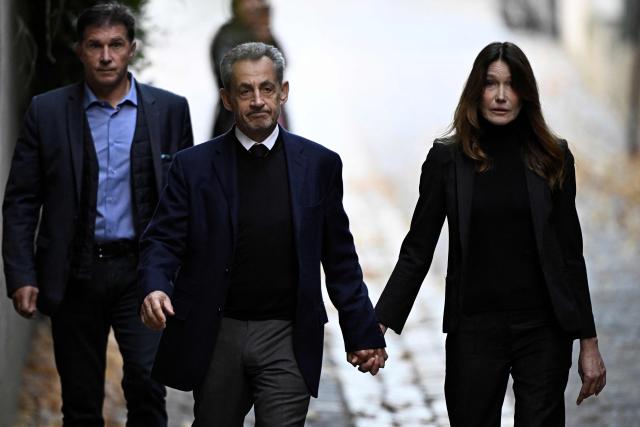(FILES) France's former president Nicolas Sarkozy (C), with his wife Carla Bruni-Sarkozy, leaves his residence to present himself to La Sante Prison for incarceration on a five-year prison sentence after being convicted of criminal conspiracy over a plan for late Libyan dictator Moamer Kadhafi to fund his 2007 electoral campaign, in Paris, on October 21, 2025. French prosecutors on December 17, 2025 announced that they were seeking indictments against the former French President, his wife and nine others in an alleged witness-tampering case. (Photo by JULIEN DE ROSA / AFP)