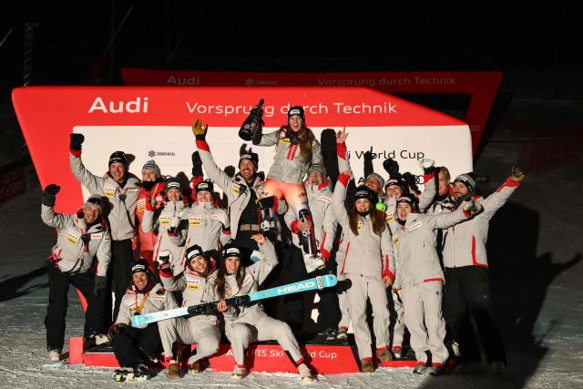 Switzerland's Camille Rast (C) celebrates with her team on the podium after the FIS Alpine Skiing women's World Cup 2025-2026 slalom in Courchevel, French Alps, on December 16, 2025. (Photo by Jeff PACHOUD / AFP)