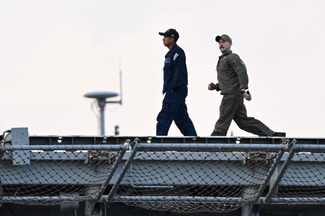 Military personel are seen on the Wasp-class amphibious assault ship USS Iwo Jima (LHD7) docked at Rafael Cordero Santiago Port of the America on December 16, 2025 in Ponce, Puerto Rico. President Donald Trump administration is conducting a military campaign in the Caribbean and eastern Pacific, deploying naval and air forces for what it calls an anti-drugs offensive. (Photo by Miguel J. Rodriguez Carrillo / AFP)