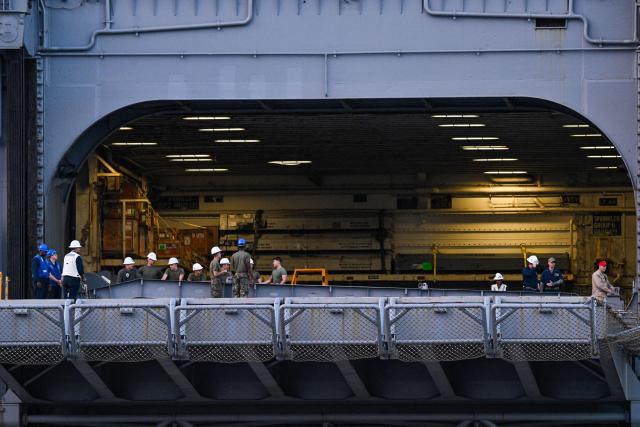 Military personel are seen on the Wasp-class amphibious assault ship USS Iwo Jima (LHD7) docked at Rafael Cordero Santiago Port of the America on December 16, 2025 in Ponce, Puerto Rico. President Donald Trump administration is conducting a military campaign in the Caribbean and eastern Pacific, deploying naval and air forces for what it calls an anti-drugs offensive. (Photo by Miguel J. Rodriguez Carrillo / AFP)