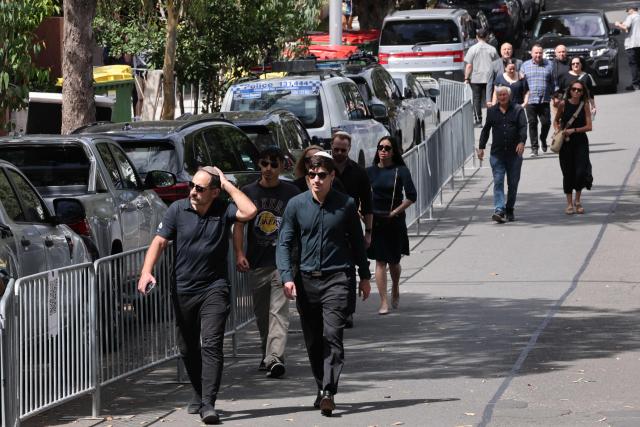 People arrive for the funeral of rabbi Eli Schlanger, who was killed in the December 14 Bondi beach shooting attack, at the Chabad of Bondi Synagogue in Sydney on December 17, 2025. Mourners cried on December 17 as they wheeled the coffin into the first funeral service for victims of the Bondi Beach mass shooting, an AFP journalist saw. Huge crowds are expected to cram the Chabad of Bondi Synagogue in Sydney to pay their respects to slain rabbi Eli Schlanger, the first of 15 victims to be laid to rest. (Photo by DAVID GRAY / AFP)
