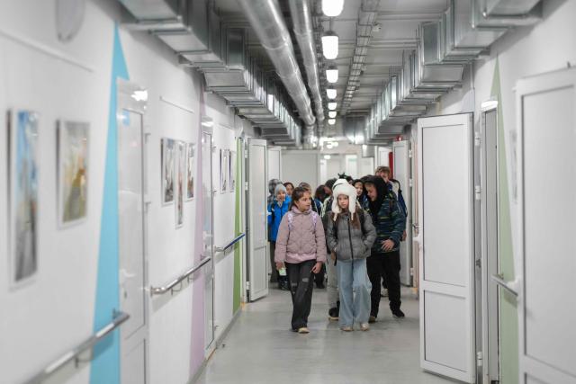 Children walk down a corridor as they leave an underground school in Kharkiv, on October 16, 2025. This new shool was built several metres below the street with no natural light. Priority is given to classes where most of the children remained in Kharkiv during the heaviest of the fighting at the start of the invasion, when Russian forces pushed into the suburbs of the city. The children spend only half their school day in the bunkers to make room for others, finishing their classes online. Researchers for the WHO who questioned 24,000 young Ukrainians from 11 to 17 at the end of 2023 found a "deterioration in the psychological wellbeing" and "significant" decrease in the happiness they felt. (Photo by OLEKSII FILIPPOV / AFP)