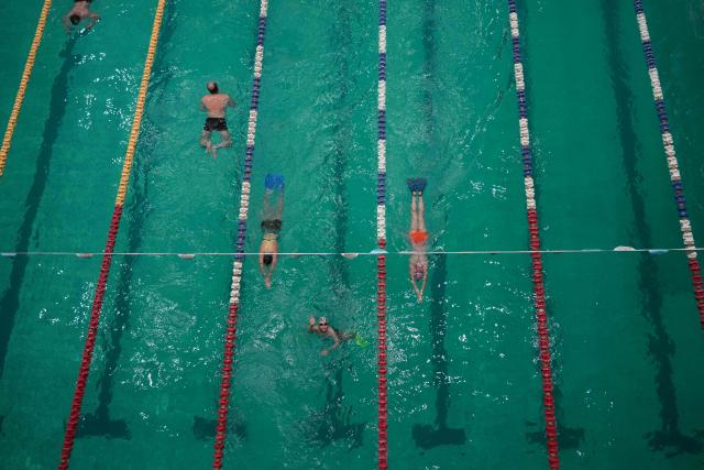 Local residents and children swim in Kharkiv’s largest swimming pool, which has been damaged multiple times by shelling, on October 17, 2025. "Water and swimming cure everything," educator Ayuna Morozova firmly believes. "First two years of Covid, then four years of war -- children are going mad," she said. The complex is now also home to a water therapy space for amputee soldiers. (Photo by OLEKSII FILIPPOV / AFP)
