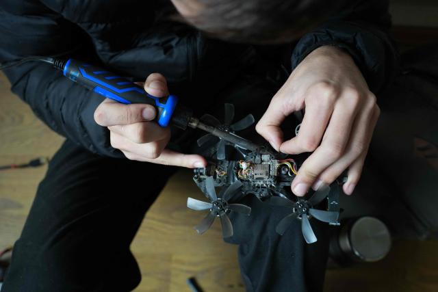 Illia Isaiev, a 18-year-old instructor at a drone pilot school, repairs a FPV drone in Kharkiv, on October 15, 2025. Some teenagers have grown a kind of emotional armour. Illia Issaiev hated it when his family fled the fighting by crossing over into Russia. The months they spent there before returning made him even more of a Ukrainian nationalist. The lean 18-year-old with steel-blue eyes claims to be a Kharkiv leader of the ultra-nationalist group Prav Molod ("The Right Youth"). (Photo by OLEKSII FILIPPOV / AFP)