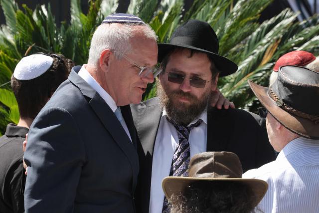Former prime minister of Australia Scott Morrison (L) arrives for the funeral of rabbi Eli Schlanger, who was killed in the December 14 Bondi beach shooting attack, at the Chabad of Bondi Synagogue in Sydney on December 17, 2025. Mourners cried on December 17 as they wheeled the coffin into the first funeral service for victims of the Bondi Beach mass shooting, an AFP journalist saw. Huge crowds are expected to cram the Chabad of Bondi Synagogue in Sydney to pay their respects to slain rabbi Eli Schlanger, the first of 15 victims to be laid to rest. (Photo by DAVID GRAY / AFP)