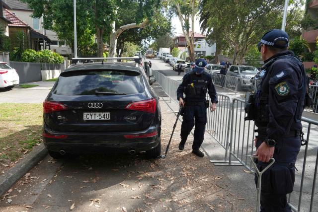Police perform a sweep outside the Chabad of Bondi Synagogue in Sydney on December 17, 2025, during the funeral of rabbi Eli Schlanger, who was killed in the December 14 Bondi Beach mass shooting. Australia held the first funeral on December 17 for victims of the Bondi Beach mass shooting, as large crowds gathered to grieve a rabbi slain in the attack. Sajid Akram and his son Naveed opened fire on a Jewish festival at the famed surf beach on December 14 evening, killing 15 people and wounding dozens more. (Photo by Mark Baker / POOL / AFP)