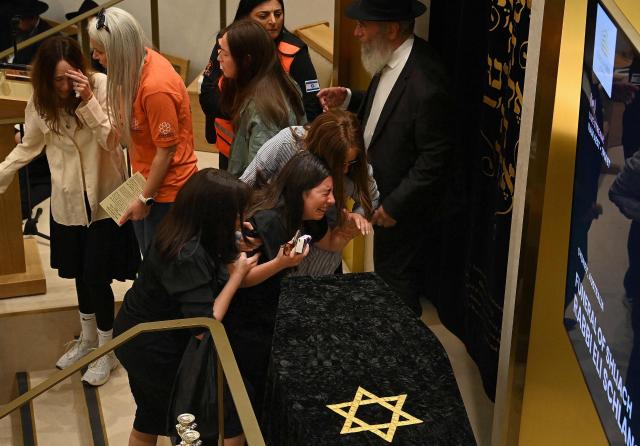 Relatives of rabbi Eli Schlanger, who was killed in the December 14 Bondi beach shooting attack, lean over his coffin during his funeral at the Chabad of Bondi Synagogue in Sydney on December 17, 2025. Australia held the first funeral on December 17 for victims of the Bondi Beach mass shooting, as large crowds gathered to grieve a rabbi slain in the attack. Sajid Akram and his son Naveed opened fire on a Jewish festival at the famed surf beach on December 14 evening, killing 15 people and wounding dozens more. (Photo by Kate Geraghty / POOL / AFP)