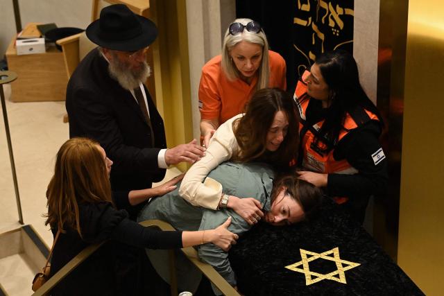 TOPSHOT - Relatives of rabbi Eli Schlanger, who was killed in the December 14 Bondi beach shooting attack, lean over his coffin during his funeral at the Chabad of Bondi Synagogue in Sydney on December 17, 2025. Australia held the first funeral on December 17 for victims of the Bondi Beach mass shooting, as large crowds gathered to grieve a rabbi slain in the attack. Sajid Akram and his son Naveed opened fire on a Jewish festival at the famed surf beach on December 14 evening, killing 15 people and wounding dozens more. (Photo by Kate Geraghty / POOL / AFP)
