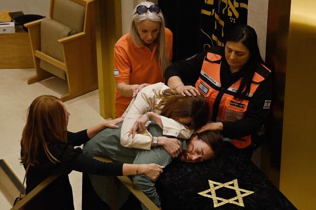 Relatives of rabbi Eli Schlanger, who was killed in the December 14 Bondi beach shooting attack, lean over his coffin during his funeral at the Chabad of Bondi Synagogue in Sydney on December 17, 2025. Australia held the first funeral on December 17 for victims of the Bondi Beach mass shooting, as large crowds gathered to grieve a rabbi slain in the attack. Sajid Akram and his son Naveed opened fire on a Jewish festival at the famed surf beach on December 14 evening, killing 15 people and wounding dozens more. (Photo by Kate Geraghty / POOL / AFP)