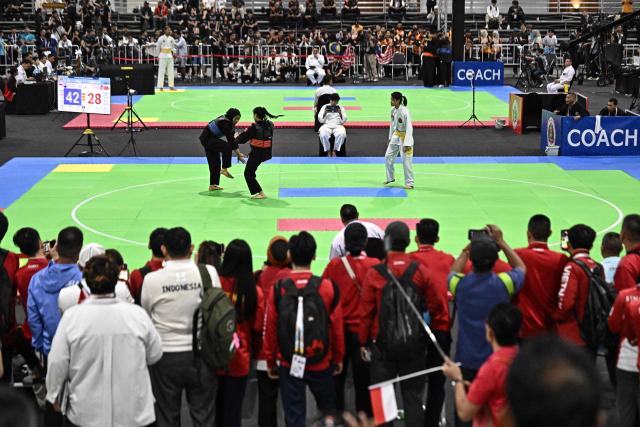 Indonesia’s Safira Dwi Meilani (L) competes against Vietnam’s Thi Hai Quyen Duong (red) in the women's individual Pencat Silat final during the 33rd Southeast Asian Games (SEA Games) at IMPACT Arena in Nonthaburi on December 17, 2025. (Photo by Lillian SUWANRUMPHA / AFP)
