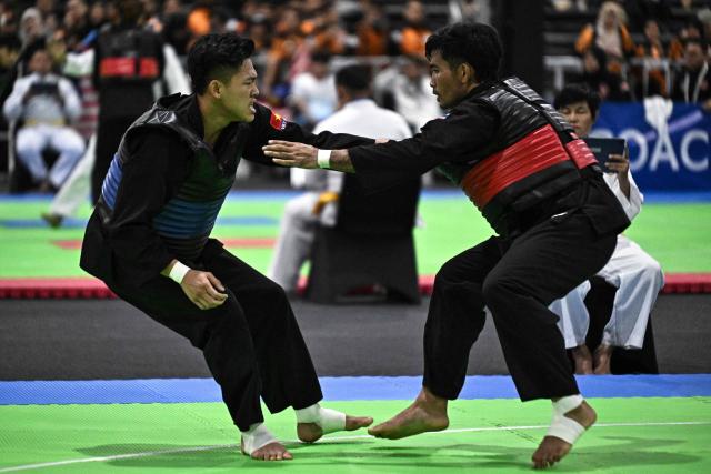 Thailand’s Anuntaya Niyompan (R) competes against Malaysia’s Ummi Mashitah Hassan (L) in the women's individual Pencat Silat final during the 33rd Southeast Asian Games (SEA Games) at IMPACT Arena in Nonthaburi on December 17, 2025. (Photo by Lillian SUWANRUMPHA / AFP)