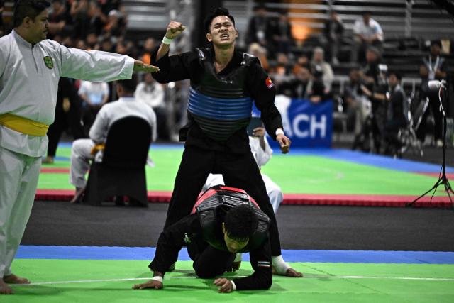 Vietnam’s Tan Sang Nguyen (top) reacts after winning against Thailand’s Suthat Bunchit (bottom) in the men’s individual Pencat Silat final during the 33rd Southeast Asian Games (SEA Games) at IMPACT Arena in Nonthaburi on December 17, 2025. (Photo by Lillian SUWANRUMPHA / AFP)
