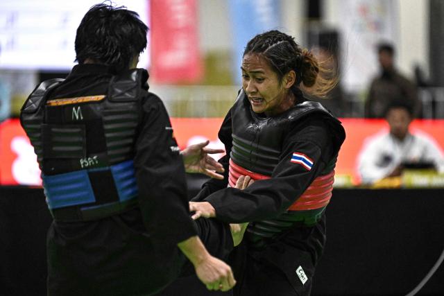 Thailand’s Anuntaya Niyompan (R) competes against Malaysia’s Ummi Mashitah Hassan (L) in the women's individual Pencat Silat final during the 33rd Southeast Asian Games (SEA Games) at IMPACT Arena in Nonthaburi on December 17, 2025. (Photo by Lillian SUWANRUMPHA / AFP)