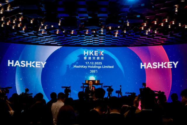 CEO of HashKey Group Xiao Feng (C) attends the company's initial public offering (IPO) launch at the Hong Kong Stock Exchange on December 17, 2025. Hong Kong's biggest licensed cryptocurrency exchange began trading on December 17 as the city pushes to become a global hub for digital units despite Beijing's tough stance on the technology. (Photo by Tommy WANG / AFP)