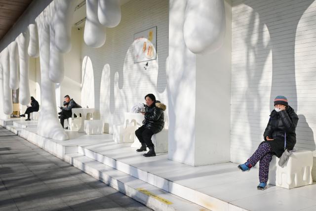 People rest outside a dessert shop in Beijing on December 17, 2025. (Photo by WANG Zhao / AFP)