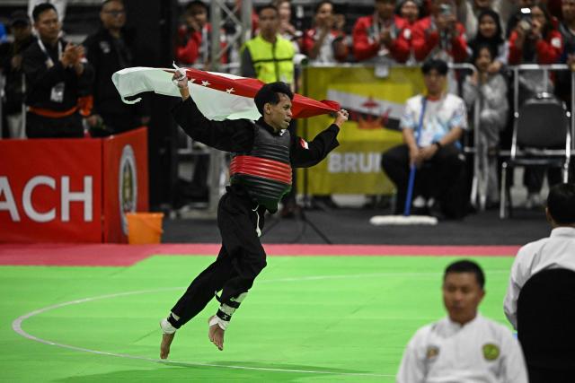Singapore’s Dhani Andika Bin Razau celebrates after winning against Indonesia’s Khoirudin Mustakim in the men’s individual under 45kg Pencat Silat final during the 33rd Southeast Asian Games (SEA Games) at IMPACT Arena in Nonthaburi on December 17, 2025. (Photo by Lillian SUWANRUMPHA / AFP)