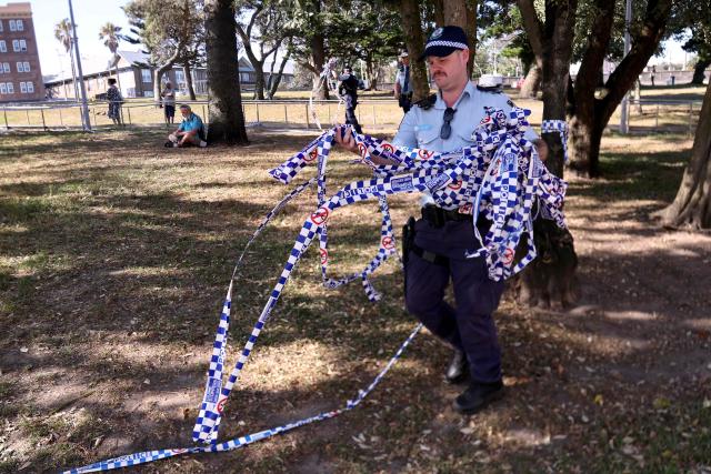 Police officers remove police tape from the scene of Sunday’s shooting at Bondi Beach, in Sydney on December 17, 2025. Police charged alleged Bondi killer Naveed Akram with terrorism, 15 counts of murder and a litany of other crimes after Australia's worst mass shooting in decades. (Photo by DAVID GRAY / AFP)
