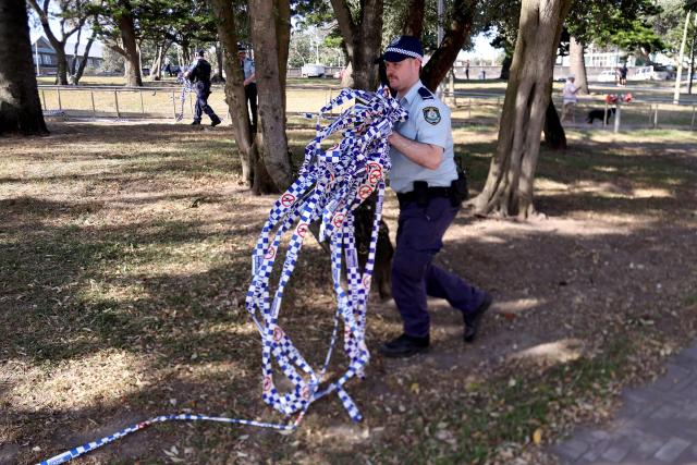 Police officers remove police tape from the scene of Sunday’s shooting at Bondi Beach, in Sydney on December 17, 2025. Police charged alleged Bondi killer Naveed Akram with terrorism, 15 counts of murder and a litany of other crimes after Australia's worst mass shooting in decades. (Photo by DAVID GRAY / AFP)