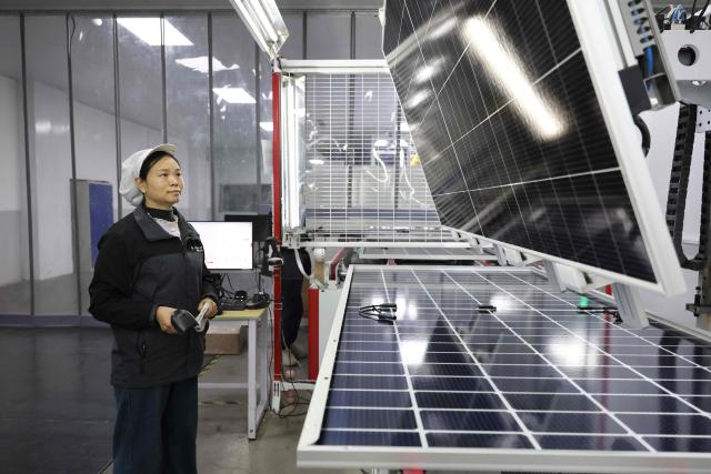 A worker produces solar module at a solar energy technology company in Huaian, in China’s eastern Jiangsu province on December 17, 2025. (Photo by AFP) / China OUT