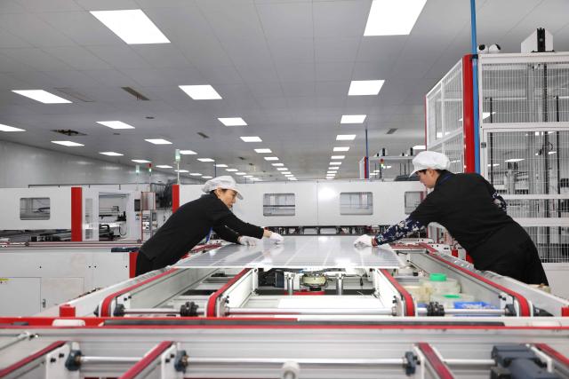 Workers produce solar module at a solar energy technology company in Huaian, in China’s eastern Jiangsu province on December 17, 2025. (Photo by AFP) / China OUT