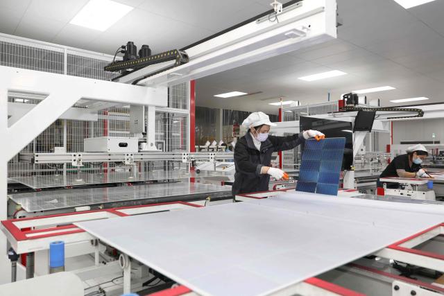 Workers produce solar module at a solar energy technology company in Huaian, in China’s eastern Jiangsu province on December 17, 2025. (Photo by AFP) / China OUT