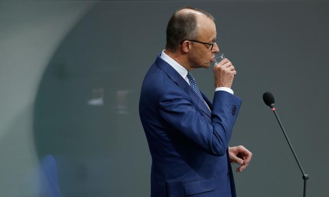 German Chancellor Friedrich Merz drinks during a question time at the Bundestag (lower house of parliament) in Berlin, on December 17, 2025. (Photo by Odd ANDERSEN / AFP)
