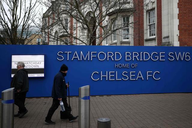 People walk outside the grounds of Stamford Bridge, the home of English Premier League team Chelsea, formally owned by Russian businessman Roman Abramovich, in London on December 17, 2025. Britain's Prime Minister Keir Starmer on December 17, 2025 warned former Chelsea owner Roman Abramovich "the clock is ticking" over the frozen £2.5 billion (3.4 billion USD) generated from the sale of the club, which has been earmarked to help Ukraine's war victims. A consortium led by US businessman Todd Boehly bought the Premier League giants after Abramovich was sanctioned following Russian President Vladimir Putin's invasion of Ukraine. (Photo by HENRY NICHOLLS / AFP)