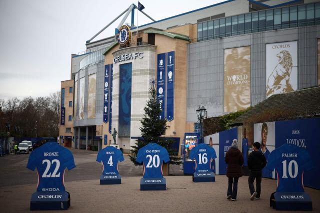 People walk outside the grounds of Stamford Bridge, the home of English Premier League team Chelsea, formally owned by Russian businessman Roman Abramovich, in London on December 17, 2025. Britain's Prime Minister Keir Starmer on December 17, 2025 warned former Chelsea owner Roman Abramovich "the clock is ticking" over the frozen £2.5 billion (3.4 billion USD) generated from the sale of the club, which has been earmarked to help Ukraine's war victims. A consortium led by US businessman Todd Boehly bought the Premier League giants after Abramovich was sanctioned following Russian President Vladimir Putin's invasion of Ukraine. (Photo by HENRY NICHOLLS / AFP)