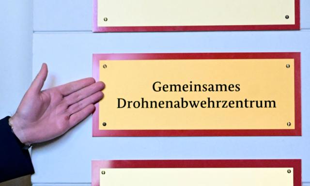German Interior Minister Alexander Dobrindt gestures in front of the sign for the 'Gemeinsame Drohnenabwehrzentrum' (Joint Drone Defense Center) during the opening of a new police antidrone center (GDAZ) in the Federal Police Directorate 11 in Berlin, Germany, on December 17, 2025. The police antidrone center (GDAZ) coordinates expertise of federal security authorities, the state police forces and the Bundeswehr in security-related drone incidents. (Photo by Tobias SCHWARZ / AFP)