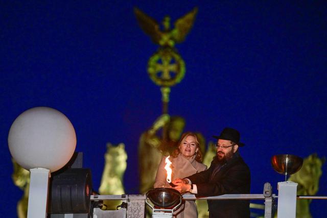 President of the Bundestag (lower house of parliament) Julia Kloeckner (L) and Rabbi Yehuda Teichtal light the menorah together during the central Hanukkah candle lighting ceremony at the Brandenburg Gate in Berlin on December 17, 2025. (Photo by John MACDOUGALL / AFP) / ALTERNATIVE CROP