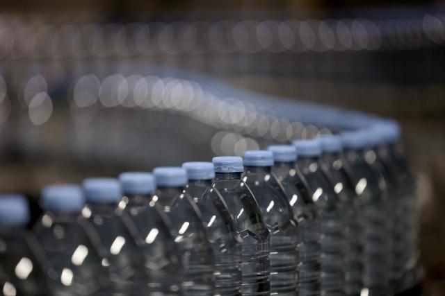 This photograph shows bottles of Evian on an assembly line at the Evian water bottling plant, in Publier, eastern France on December 16, 2025. (Photo by Alex MARTIN / AFP)