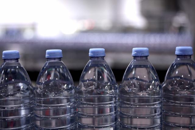 This photograph shows bottles of Evian on an assembly line at the Evian water bottling plant, in Publier, eastern France on December 16, 2025. (Photo by Alex MARTIN / AFP)