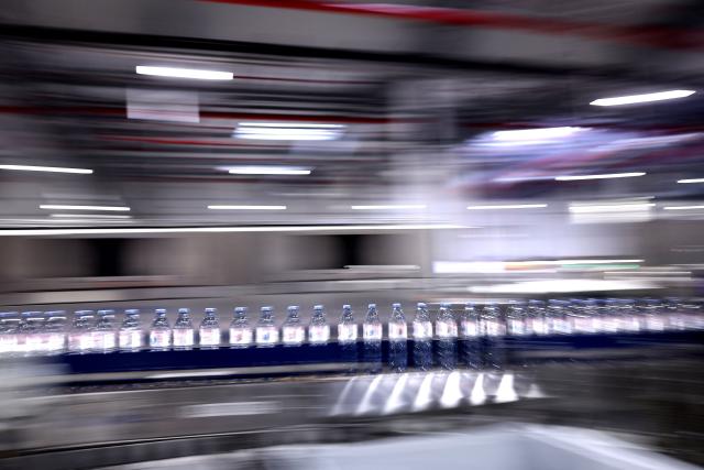 This photograph shows bottles of Evian on an assembly line at the Evian water bottling plant, in Publier, eastern France on December 16, 2025. (Photo by Alex MARTIN / AFP)