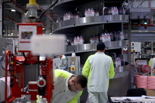 Employees work on an assembly line at the Evian water bottling plant, in Publier, eastern France on December 16, 2025. (Photo by Alex MARTIN / AFP)