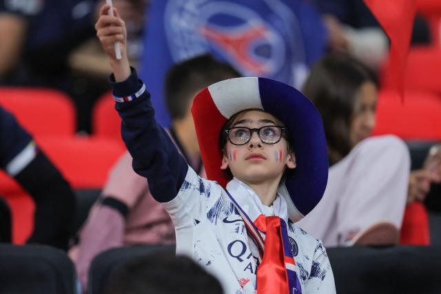A young PSG supporter cheers for his team prior to the 2025 FIFA Intercontinental Cup final football match between Paris Saint-Germain (PSG) and CR Flamengo at the Ahmad bin Ali Stadium in Al-Rayyan on the outskirts of Doha on December 17, 2025. (Photo by Karim JAAFAR / AFP)