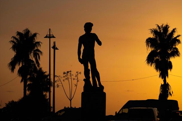 This photograph taken in the eighth arrondissement of Marseille, southeastern France on December 17, 2025 shows a copy of the statue of Michelangelo's David in Carrara marble at sunset. (Photo by MIGUEL MEDINA / AFP)