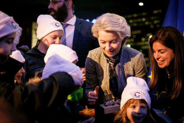 European Commission President Ursula von der Leyen receives presents from children as she takes part in the Euro-Chanukah event organized by the European Jewish Community Center (EJCC) together with the European Jewish Association (EJA) outside the European Union buildings in Brussels on December 17, 2025. (Photo by Simon Wohlfahrt / AFP)