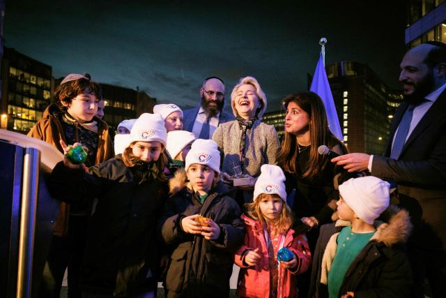 European Commission President Ursula von der Leyen receives presents from children as she takes part in the Euro-Chanukah event organized by the European Jewish Community Center (EJCC) together with the European Jewish Association (EJA) outside the European Union buildings in Brussels on December 17, 2025. (Photo by Simon Wohlfahrt / AFP)