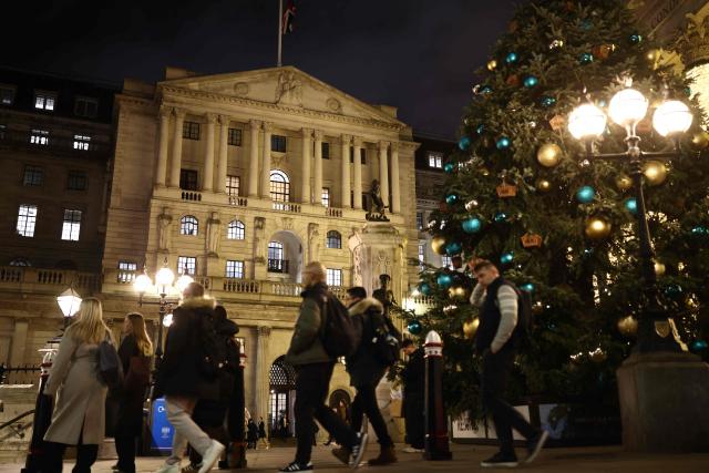 Pedestrians walk by the Bank of England building in the City of London on December 17, 2025. Britain's annual inflation rate slowed more than expected in November to 3.2 percent, official data showed December 17, cementing expectations that the Bank of England will cut its main interest rate on December 18. (Photo by Henry NICHOLLS / AFP)