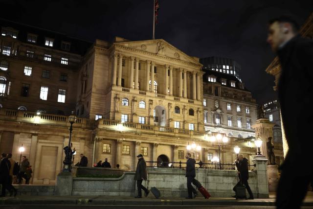 Pedestrians walk by the Bank of England building in the City of London on December 17, 2025. Britain's annual inflation rate slowed more than expected in November to 3.2 percent, official data showed December 17, cementing expectations that the Bank of England will cut its main interest rate on December 18. (Photo by Henry NICHOLLS / AFP)