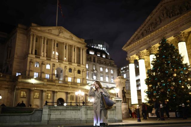 TOPSHOT - A pedestrian walks by the Bank of England building (L) and The Royal Exchange (R) in the City of London on December 17, 2025. Britain's annual inflation rate slowed more than expected in November to 3.2 percent, official data showed December 17, cementing expectations that the Bank of England will cut its main interest rate on December 18. (Photo by Henry NICHOLLS / AFP)