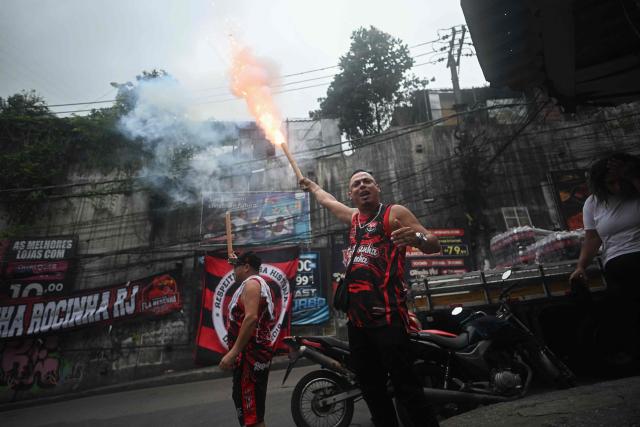 Flamengo supporters hold flares while watching the final match of the 2025 FIFA Intercontinental Cup between Paris Saint-Germain and Flamengo at Rocinha favela in Rio de Janeiro, Brazil on December 17, 2025. (Photo by MAURO PIMENTEL / AFP)