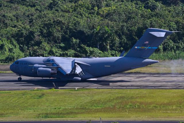 A Boeing C-17 Globemaster lands at at José Aponte de la Torre Airport, formerly Roosevelt Roads Naval Station, on December 17, 2025 in Ceiba, Puerto Rico. Aircraft movements and coordinated exercises were observed throughout the day as part of heightened regional military readiness linked to ongoing operations at US military bases and maritime security efforts in the Caribbean. President Donald Trump administration is conducting a military campaign in the Caribbean and eastern Pacific, deploying naval and air forces for what it calls an anti-drugs offensive. (Photo by Miguel J. Rodriguez Carrillo / AFP)