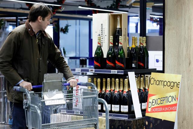 A customer looks at Champagne bottles displayed at the multinational wholesale chain 'Metro' flagship store in Nanterre during a press visit, in western Paris, on December 17, 2025. (Photo by Charlotte SIEMON / AFP)