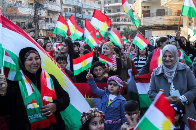 Syrian Kurds wave national flags as they celebrate Kurdish Flag Day in the city of Qamishli in northeastern Syria on December 17, 2025. (Photo by Delil SOULEIMAN / AFP)